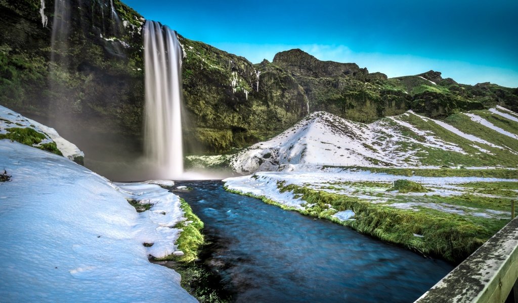 Обои трава, скалы, снег, мост, водопад, исландия, селйяландсфосс, grass, rocks, snow, bridge, waterfall, iceland, seljalandsfoss разрешение 3840x2160 Загрузить