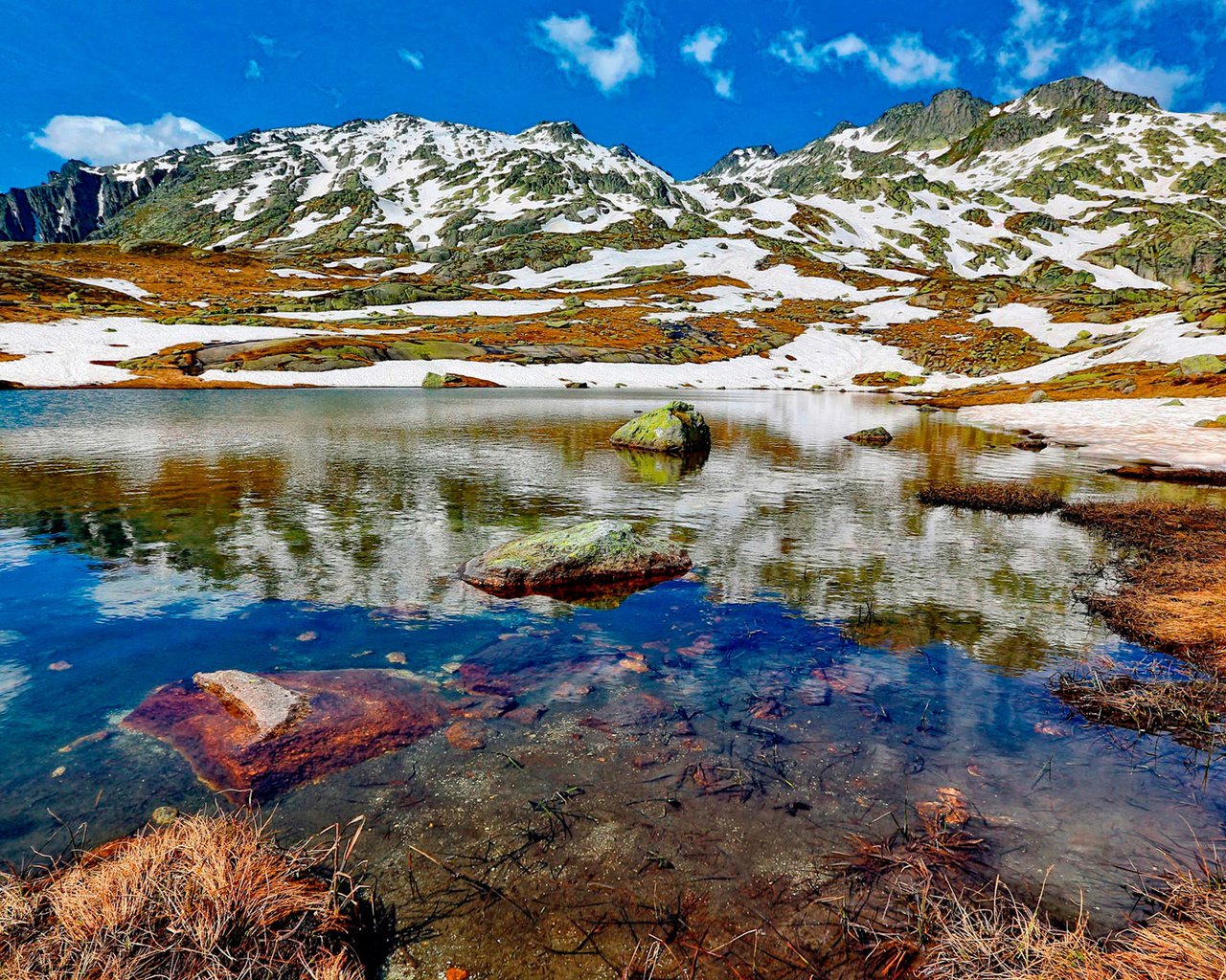 Обои небо, облака, озеро, горы, снег, камни, the sky, clouds, lake, mountains, snow, stones разрешение 1920x1265 Загрузить