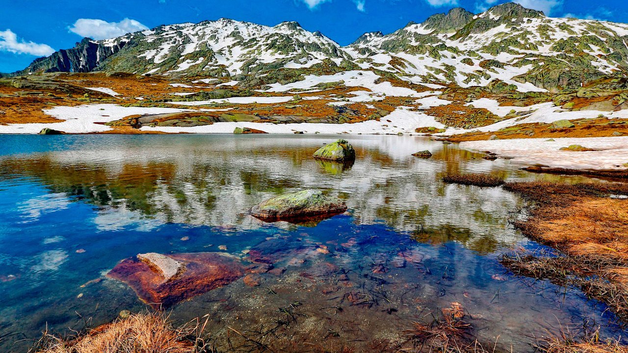 Обои небо, облака, озеро, горы, снег, камни, the sky, clouds, lake, mountains, snow, stones разрешение 1920x1265 Загрузить