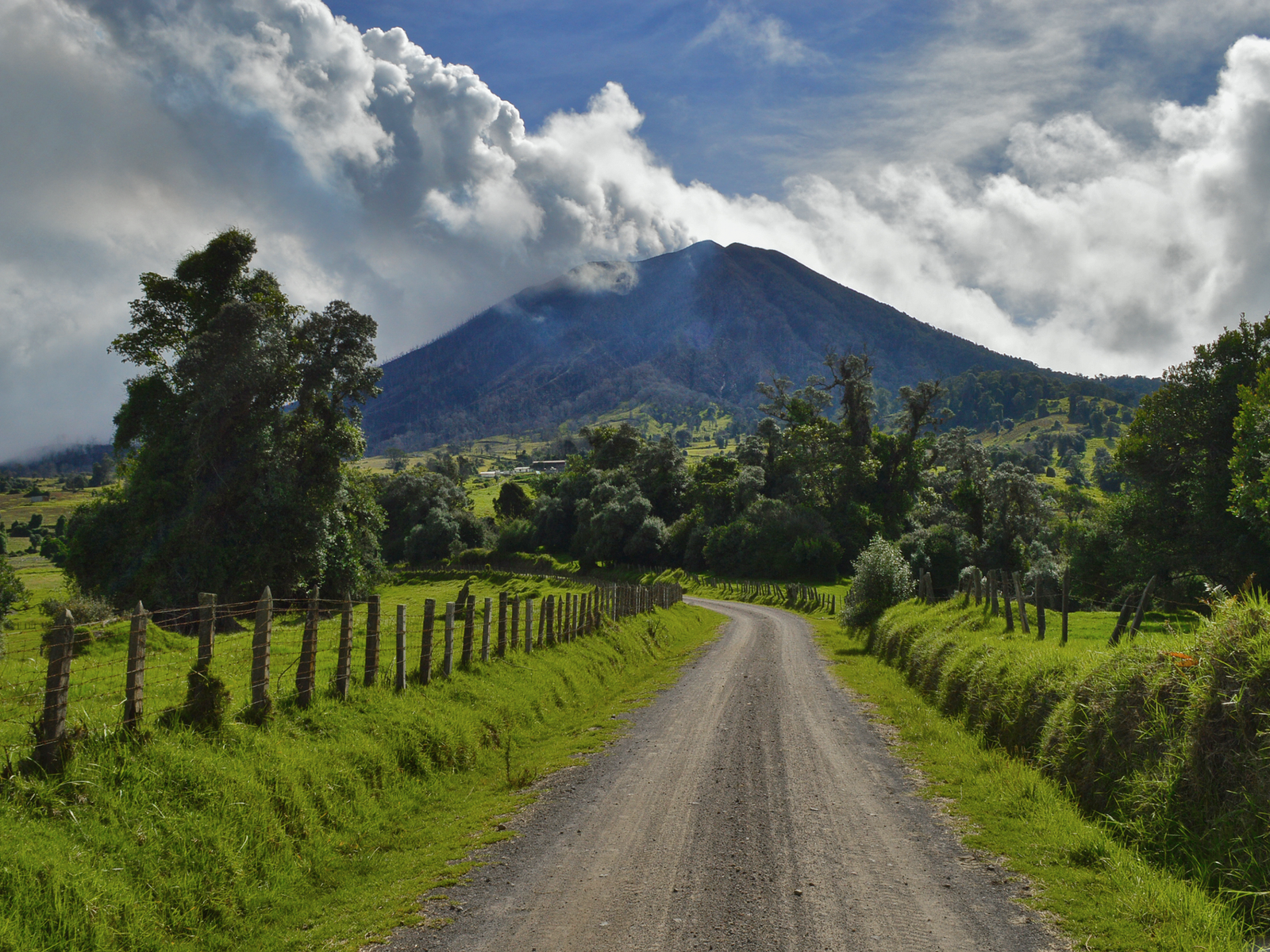 Обои небо, дорога, облака, деревья, природа, забор, вулкан, the sky, road, clouds, trees, nature, the fence, the volcano разрешение 2880x1800 Загрузить