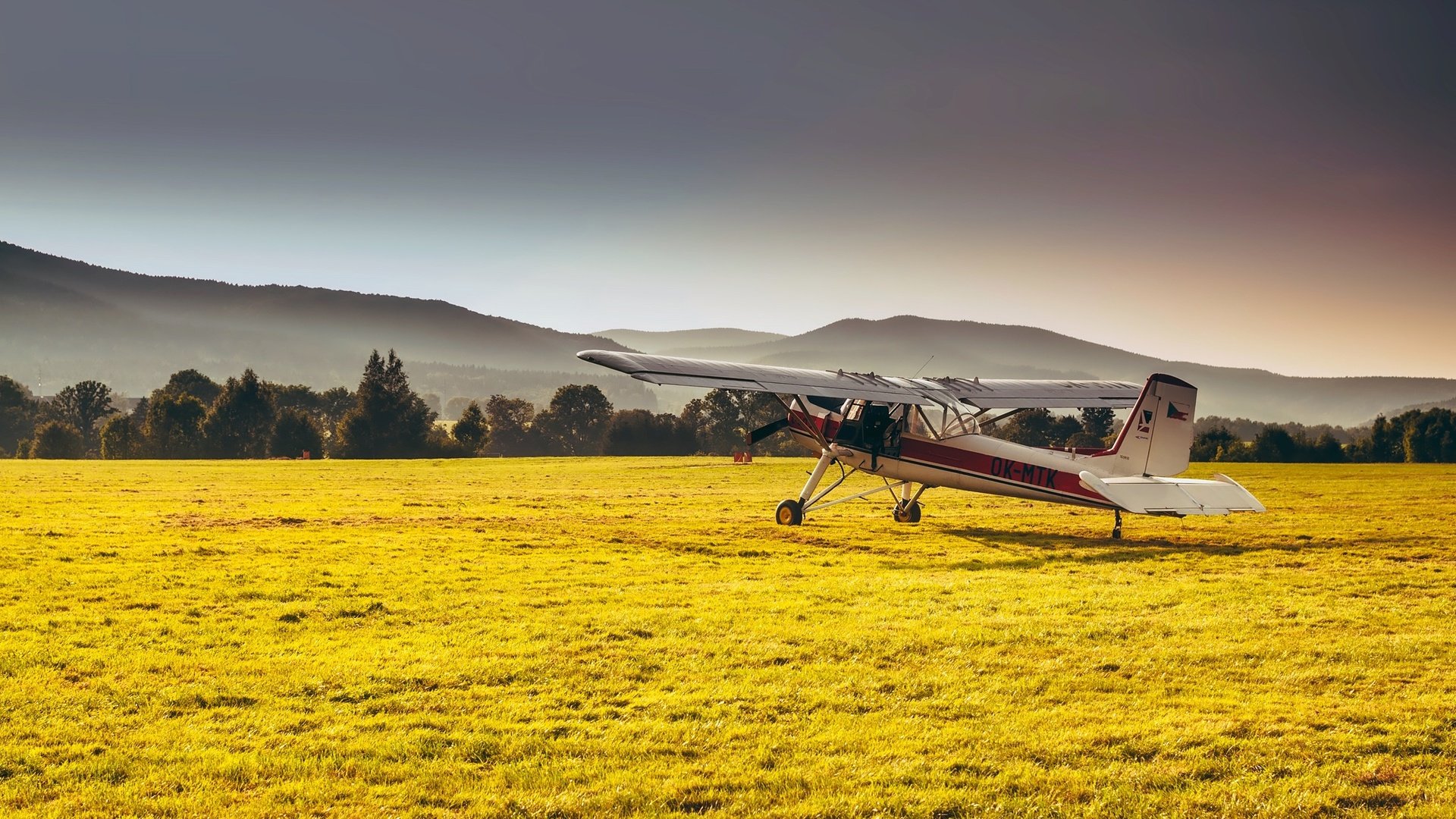 Обои трава, горы, лес, самолет, поле, дымка, солнечно, grass, mountains, forest, the plane, field, haze, sunny разрешение 2200x1461 Загрузить