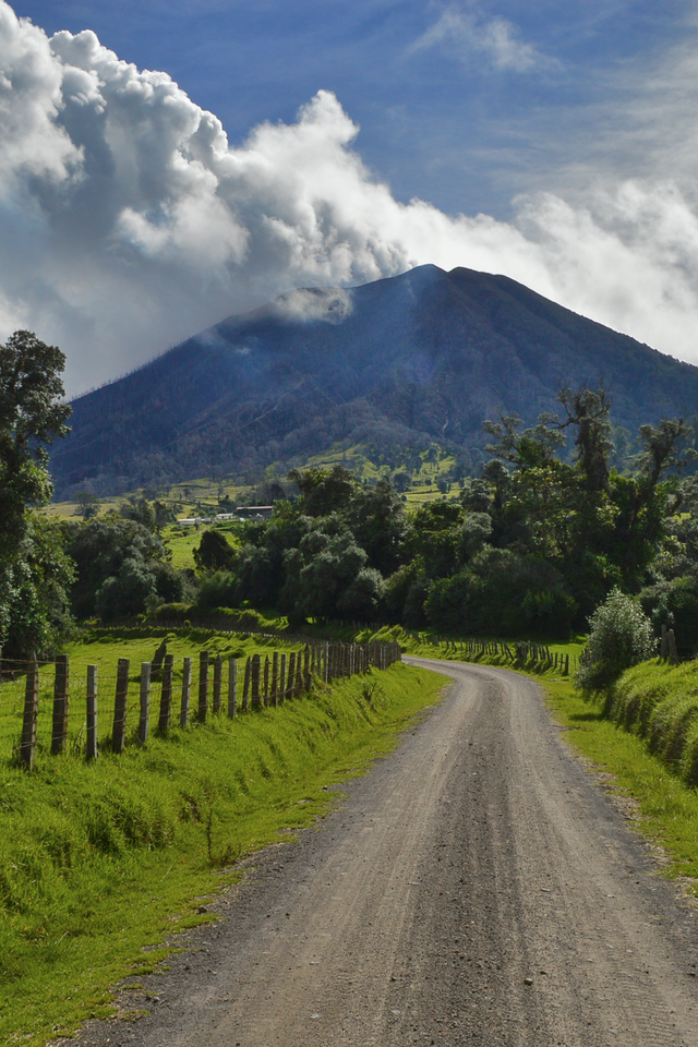 Обои небо, дорога, облака, деревья, природа, забор, вулкан, the sky, road, clouds, trees, nature, the fence, the volcano разрешение 2880x1800 Загрузить