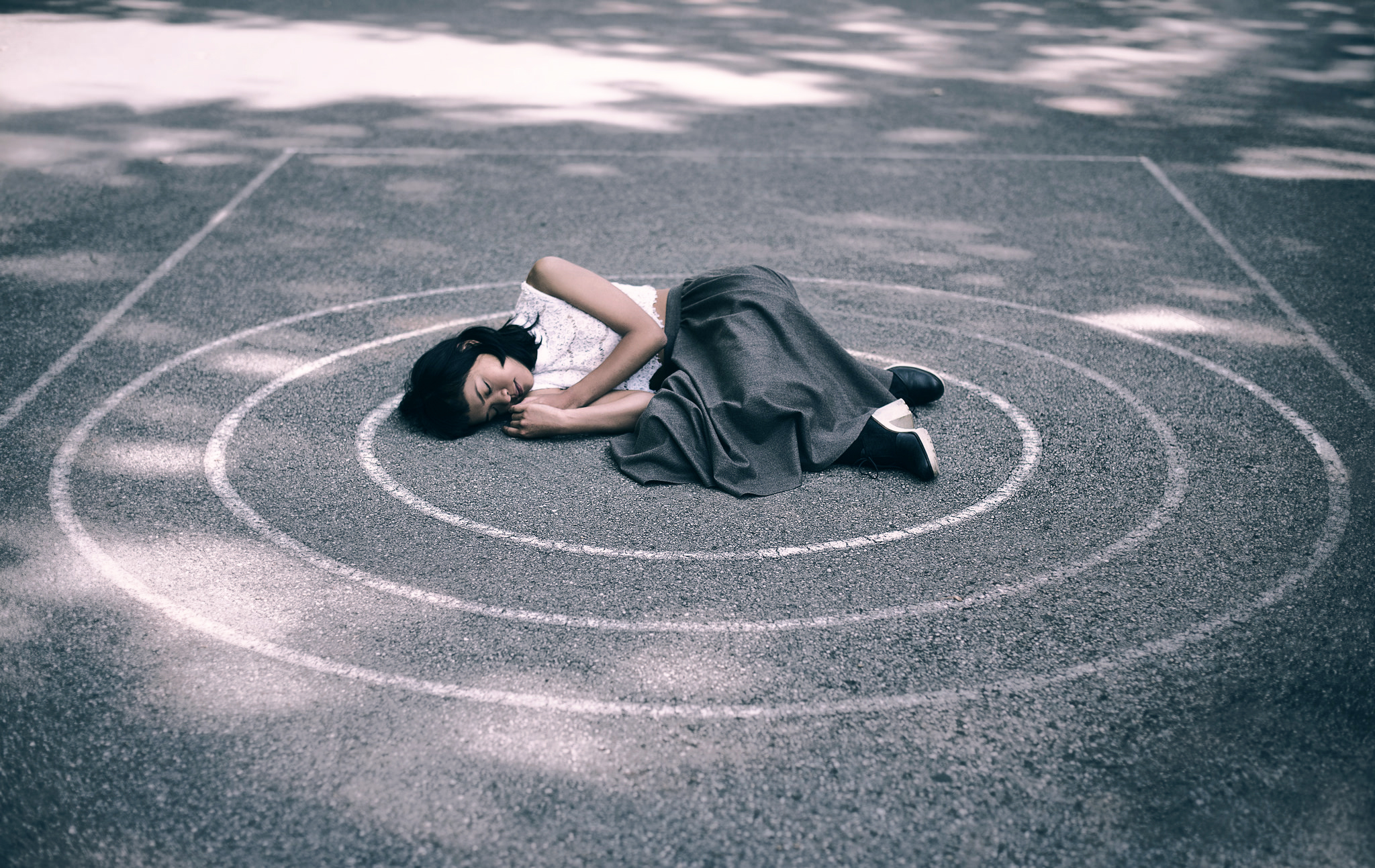 Время бежит по кругу. Девушка лежит на асфальте. Личные границы. Человек в замкнутом круге.